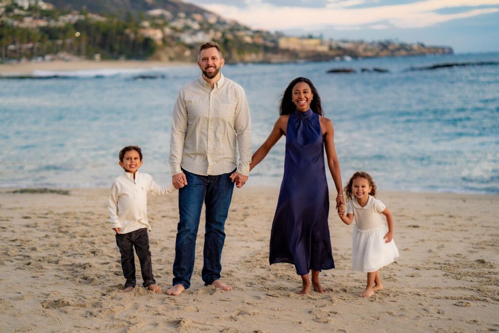 A family is standing on a beach holding hands.