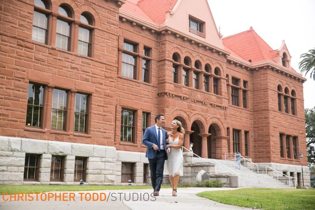 A man and woman are walking in front of the Old Orange County Courthouse
