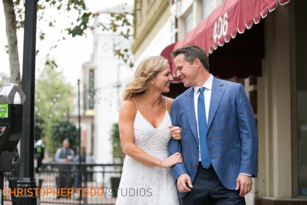 A bride and groom are walking down the street and looking at each other on Main Street in Santa Ana.