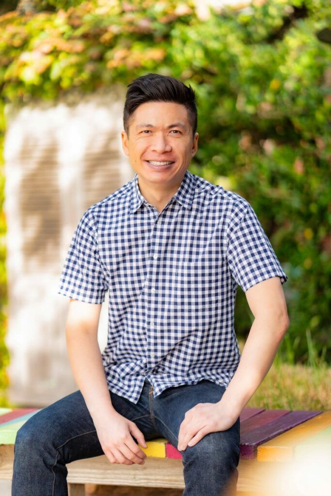 A man in a plaid shirt is sitting on a bench in front of a waterfall.