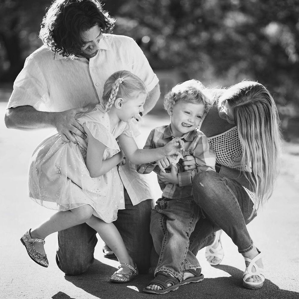 A black and white photo of a family sitting on the bike path in Huntington Beach Central Park.