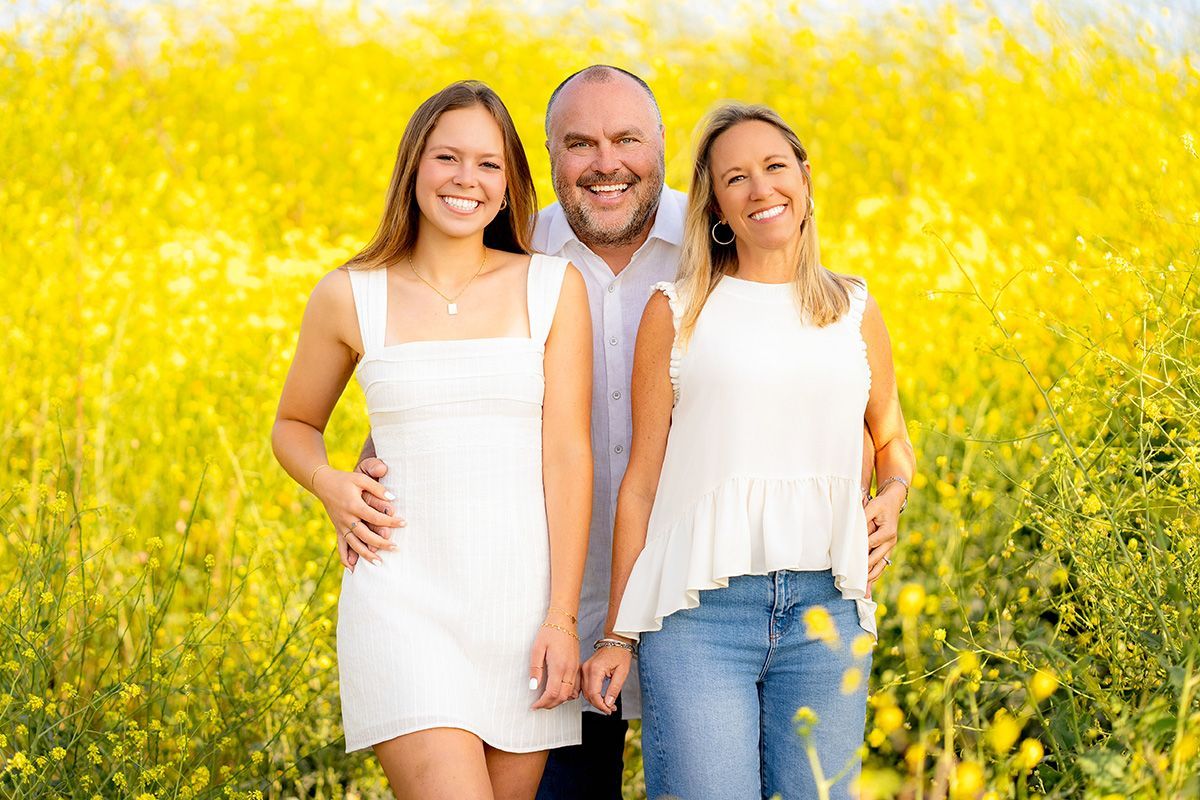 A family is posing for a picture in a field of yellow flowers.