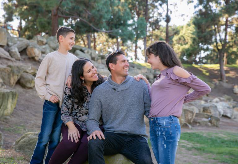 A family is sitting on a rock in a park.