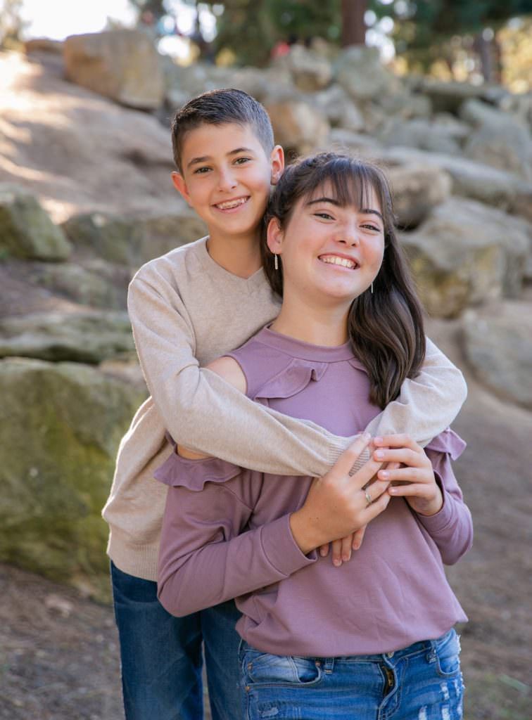 The family is sitting on rocks in Tewinkle Park in Costa Mesa.