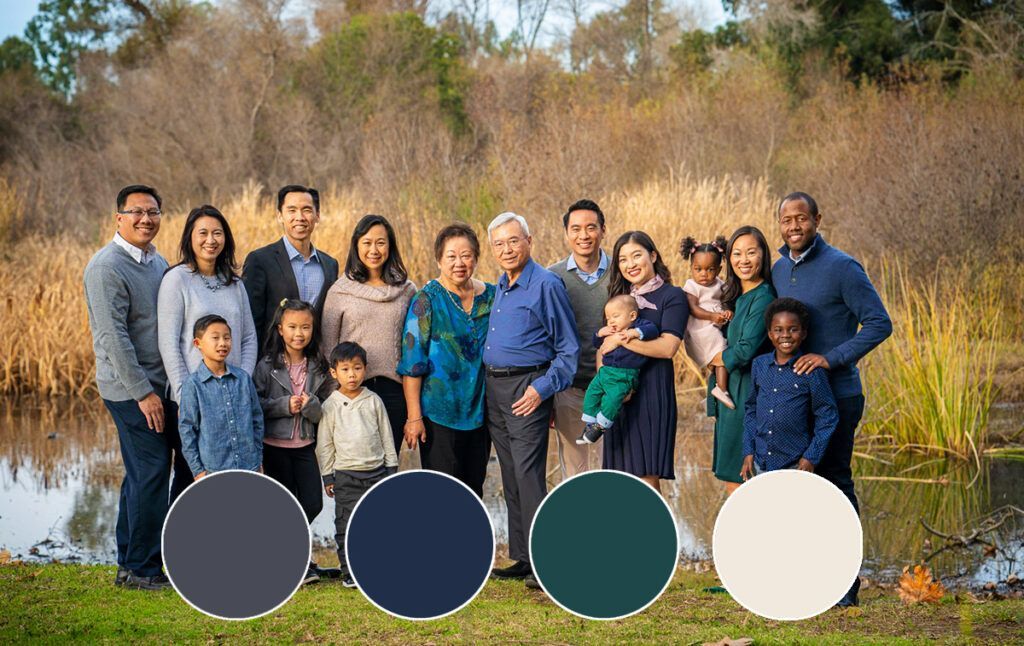 A large family is posing for a picture in front of a pond.