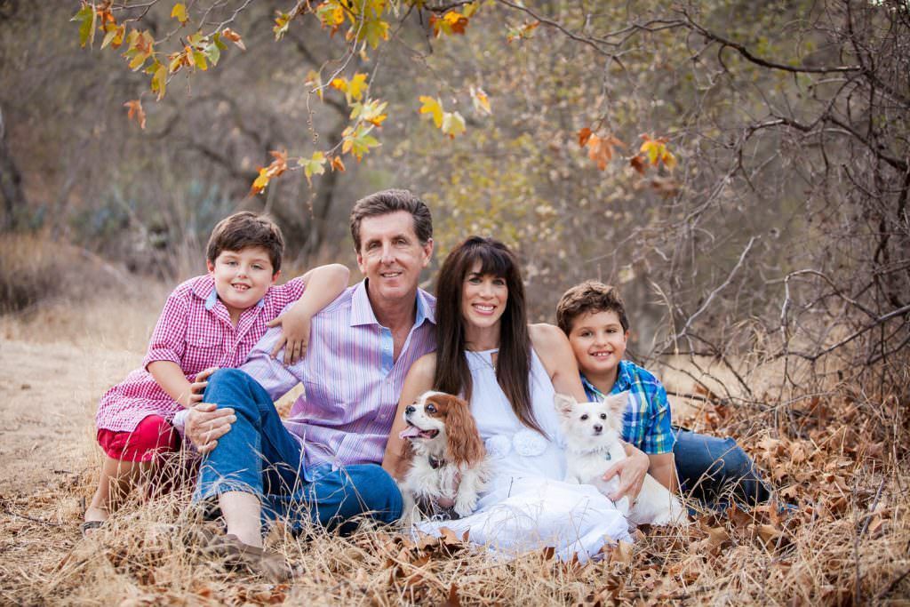 A family is sitting in the grass with a dog in Irvine regional Park California