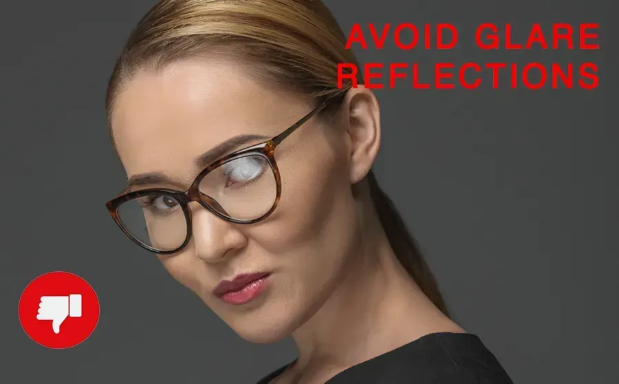 A woman wearing glasses that have too much glare is looking at the camera.