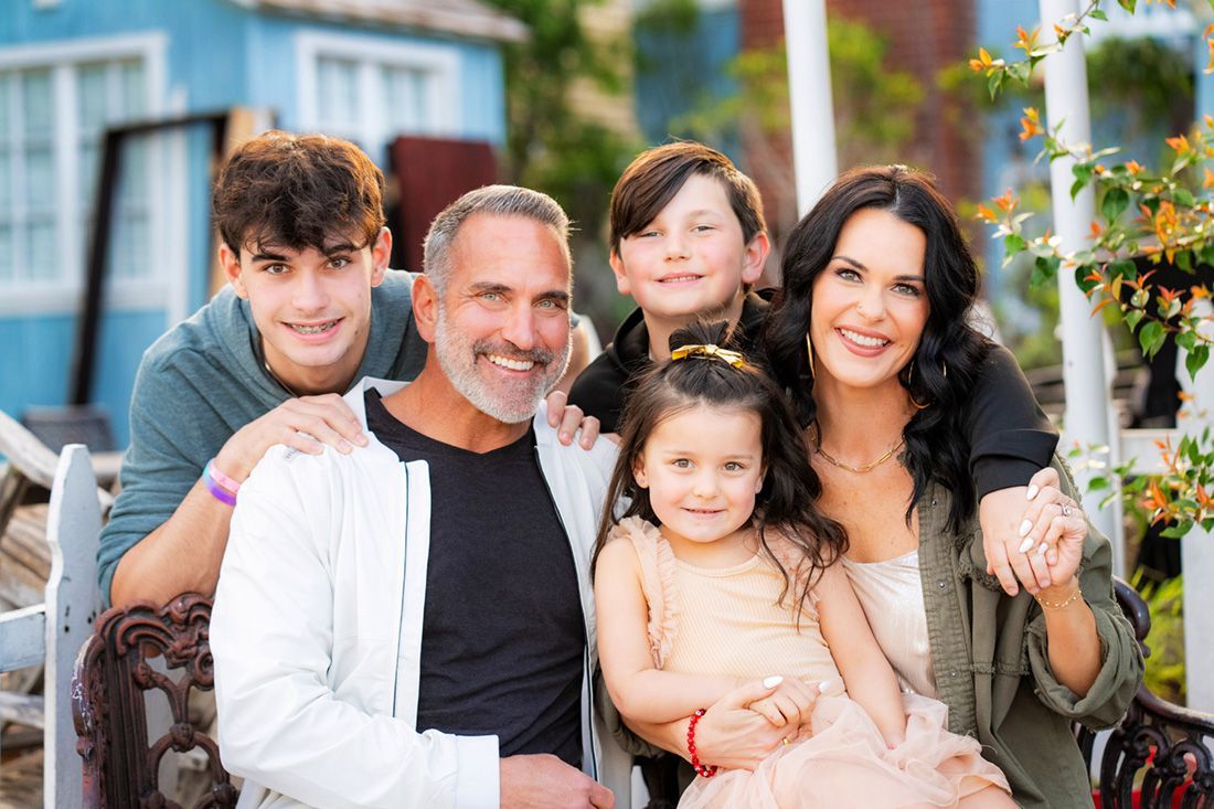 A family is posing for a picture together in front of a blue house on Balboa Peninsula. 