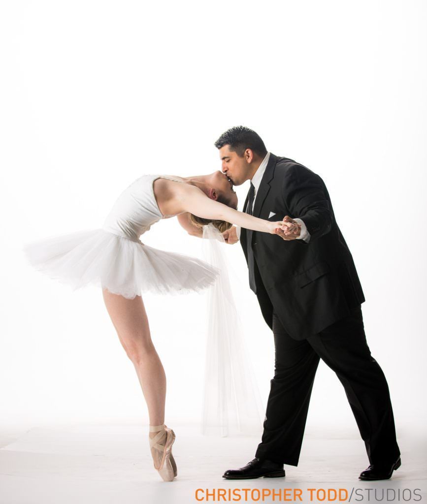 A man in a suit kisses a ballerina on the cheek