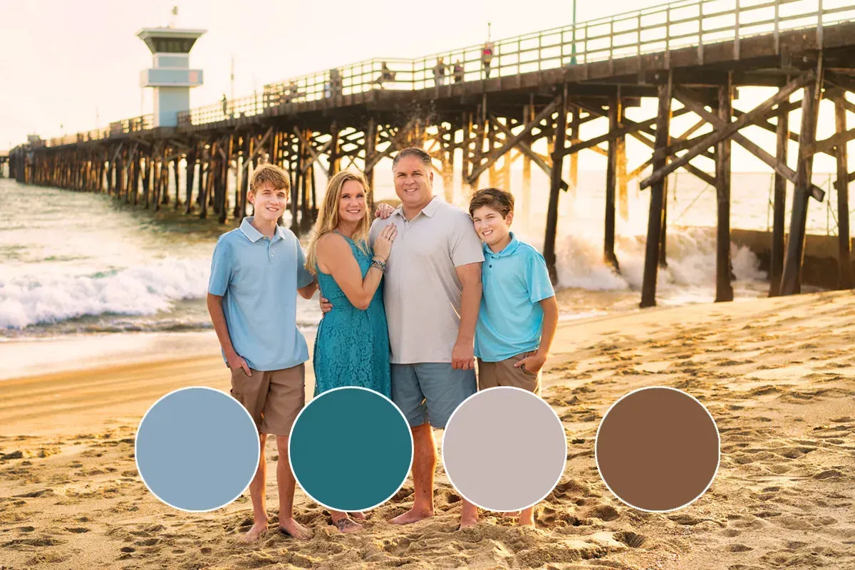 A family is posing for a picture on the beach in front of a pier.