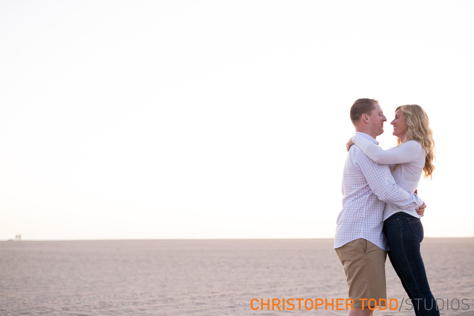 A man is holding a woman in his arms on a beach.