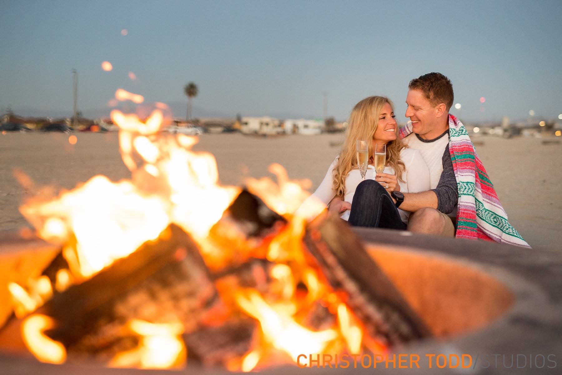 A man and a woman are sitting in front of a fire pit at Beach Blvd in Huntington beach.