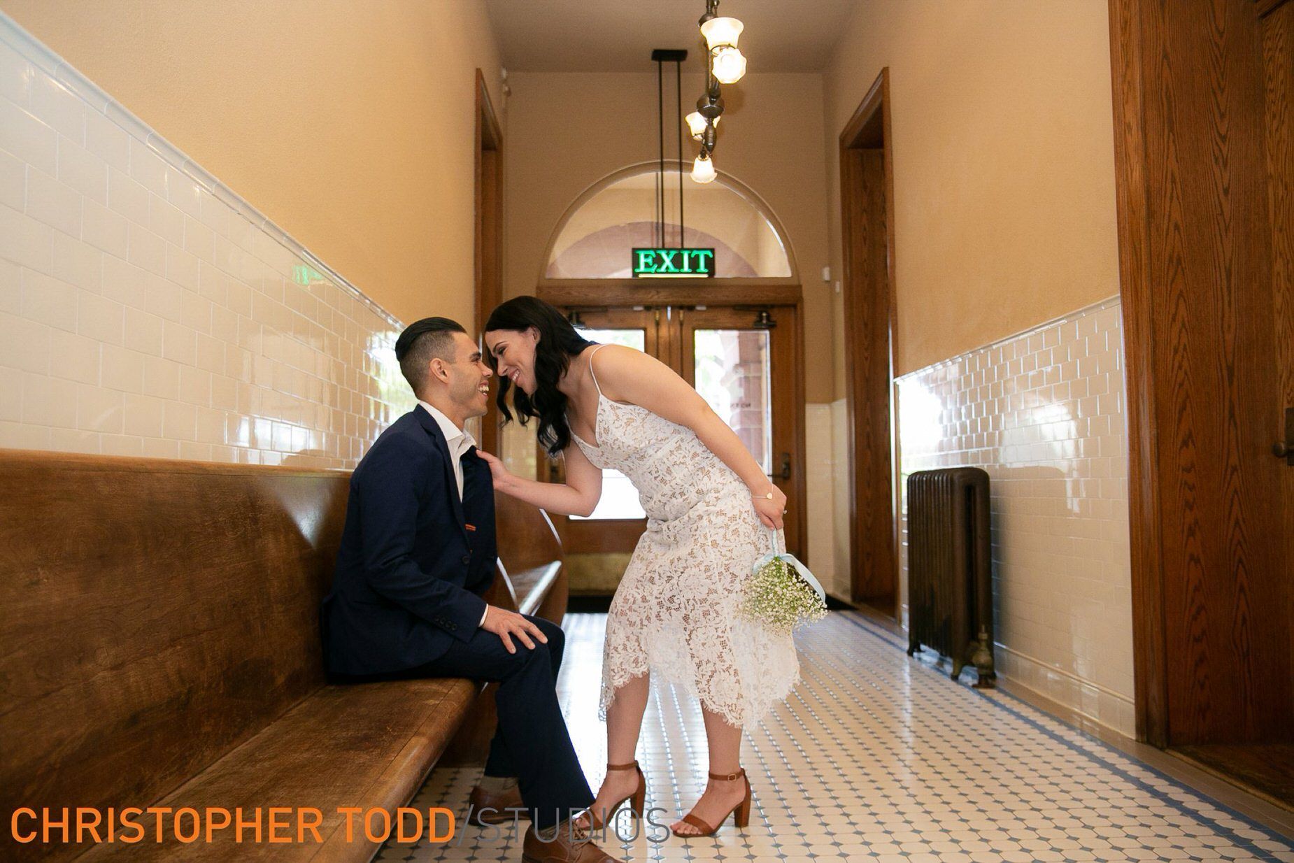 A bride and groom are sitting on a bench in the Old Courthouse in Santa Ana