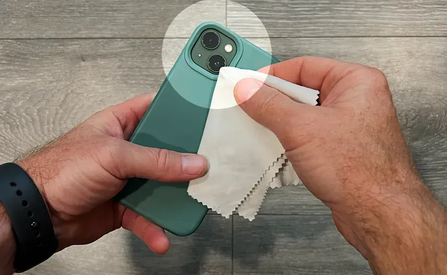 A person is cleaning a cell phone with a cloth.