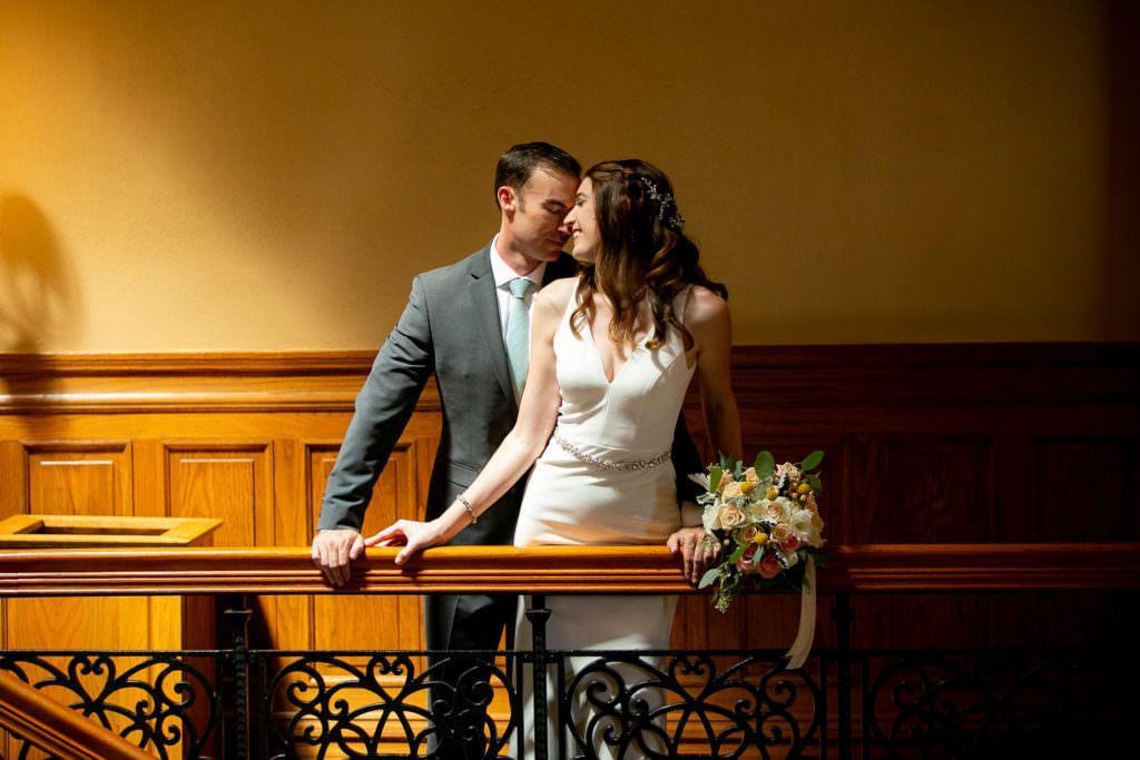 A bride and groom are posing for a picture on a balcony in the Old Courthouse in Santa Ana