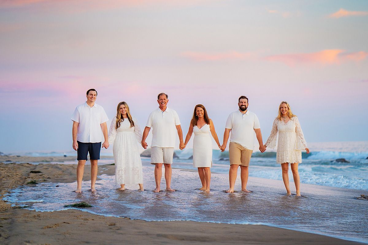 A group of people are standing on a beach holding hands.