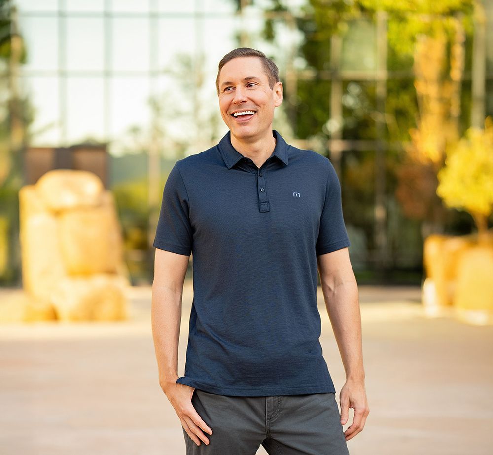 A man wearing a blue under armour polo shirt is smiling