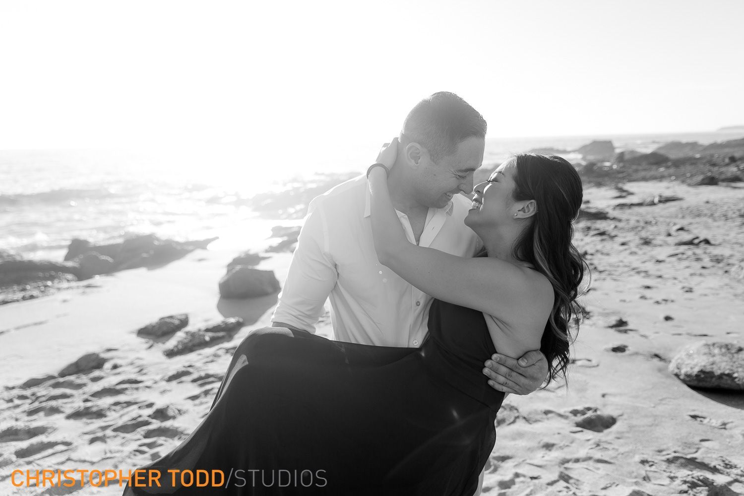 A man is holding a woman in his arms on the Newport Beach.