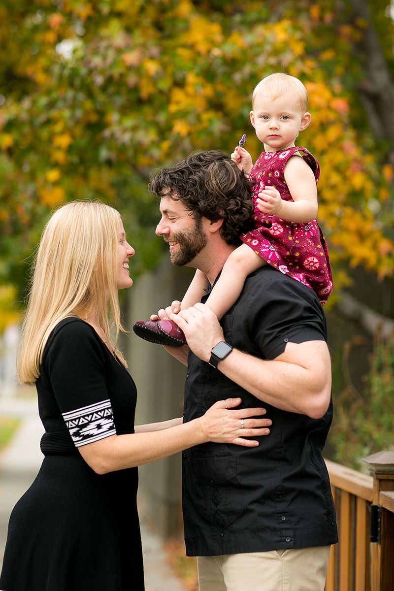 A man and woman are holding a baby on their shoulders.