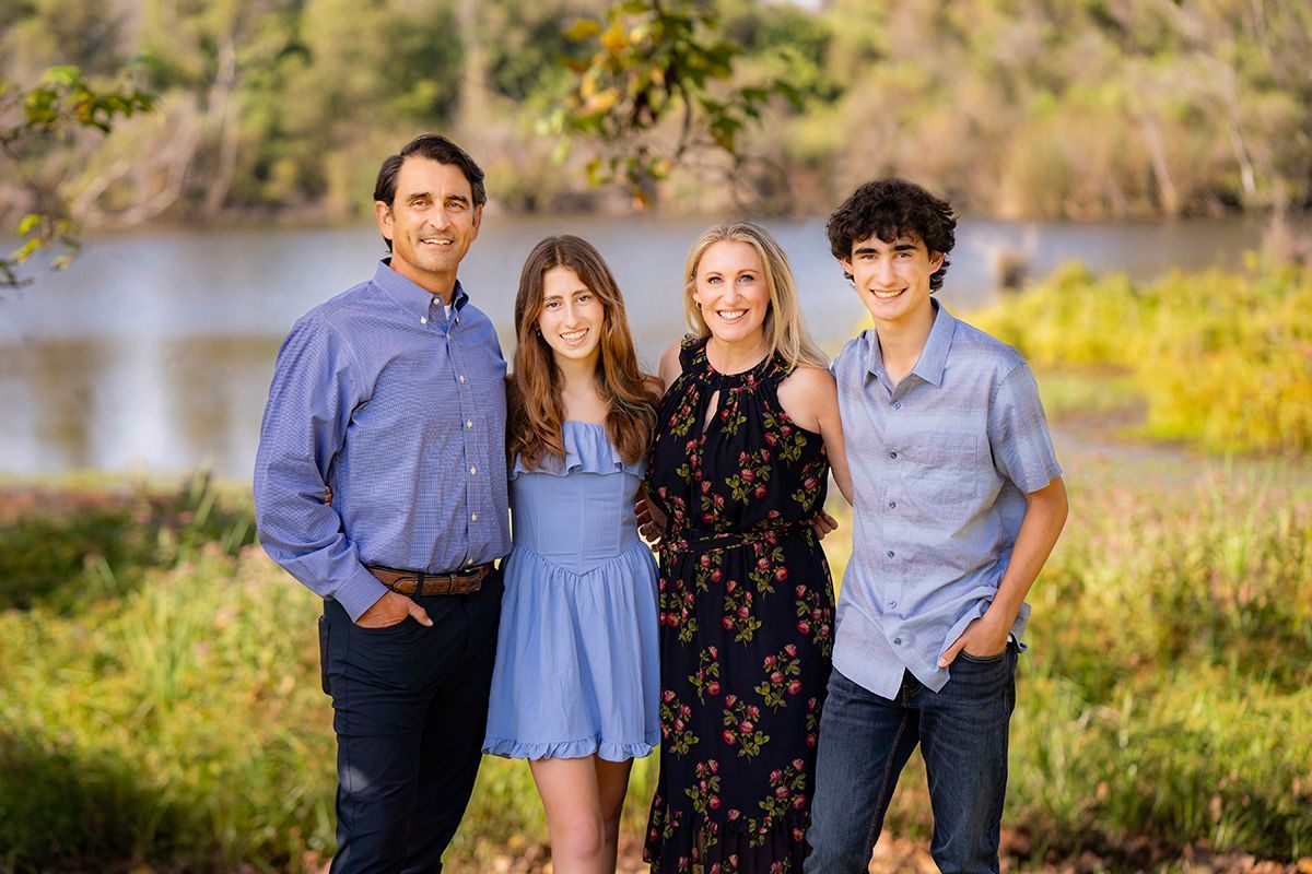 Family Photos at Best Park Location In OC A family is posing for a picture in front of a lake.