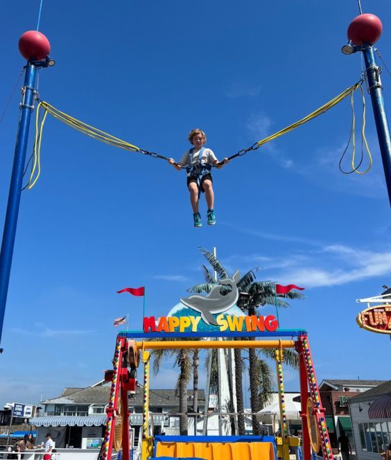 A child is flying through the air on a happy swing at the Fun Zone in Newpoirt Beach