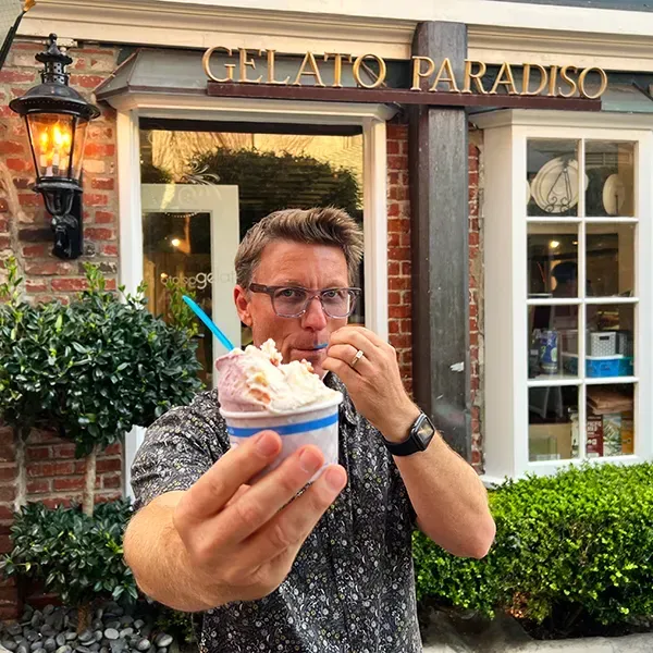 A man is eating ice cream in front of gelato paradiso