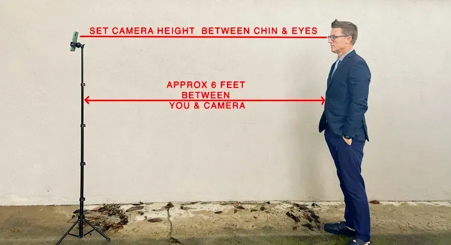A man in a suit is posing for a headshot with a phone on a light stand