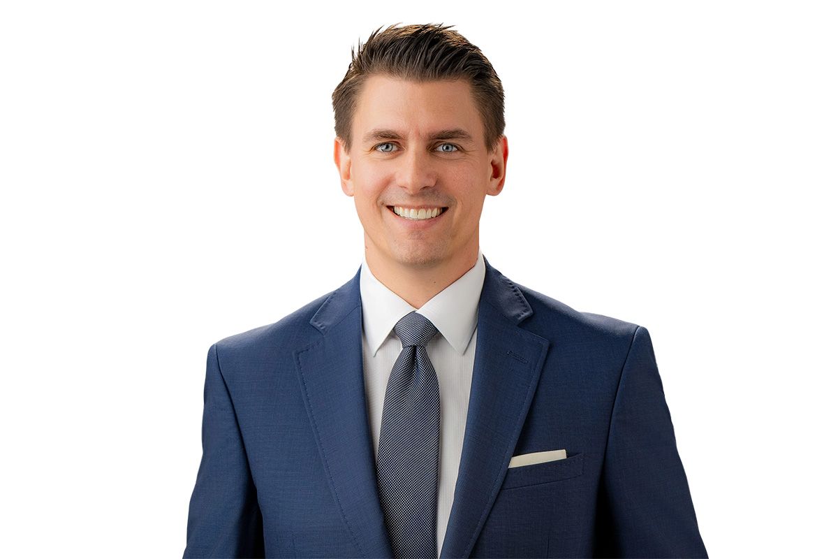 Smiling man in a blue suit and tie on a white background for wealth management headshot in Newport Beach