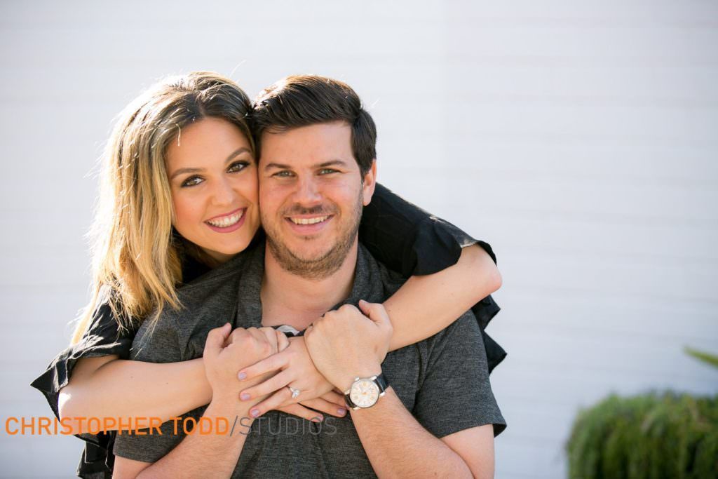 A man is carrying a woman on his back and they are smiling for the camera.