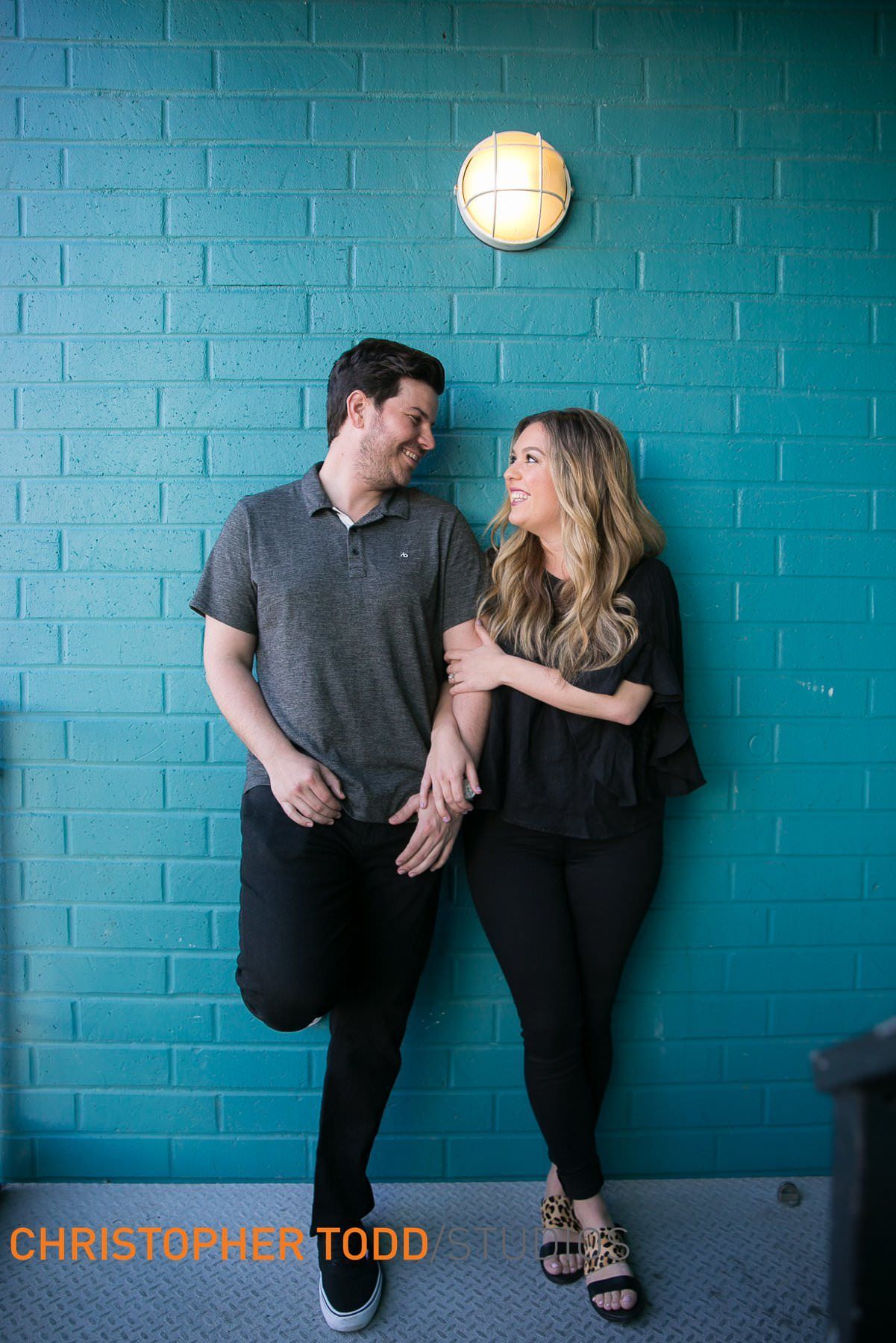 A man and a woman are standing next to each other in front of a blue brick wall in Lido Marina Village