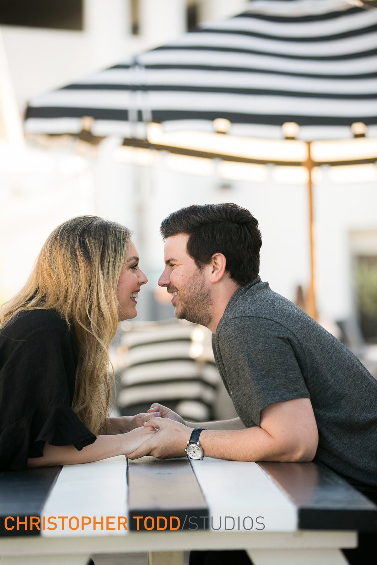 A man and a woman are sitting at a table holding hands at Nobu in Newport Beach