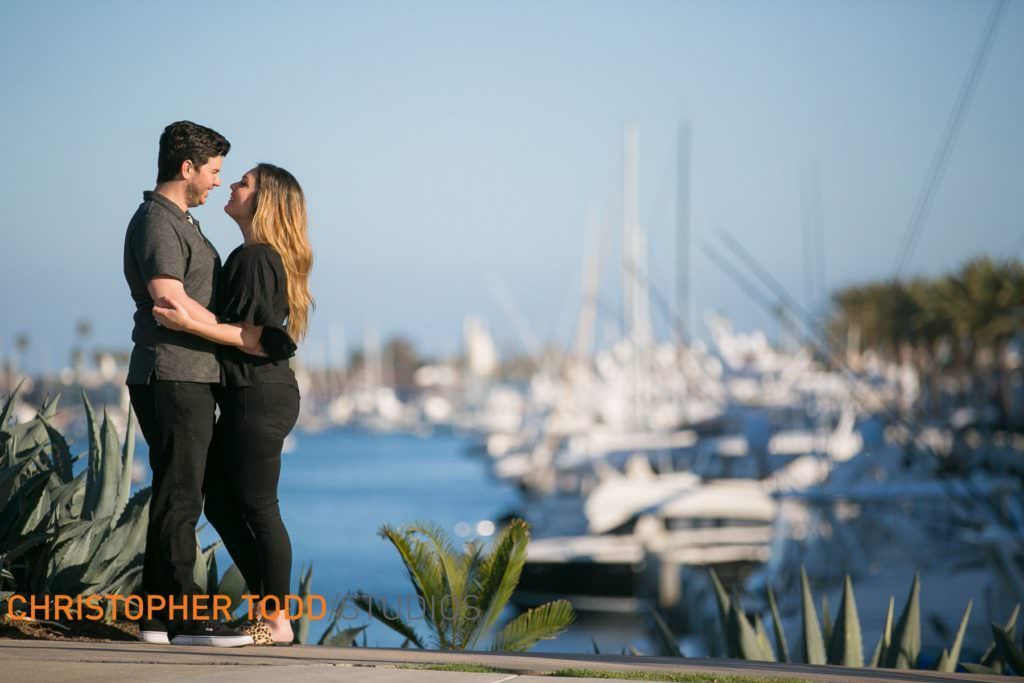 A man and a woman are standing next to each other in front of Newport Harbor