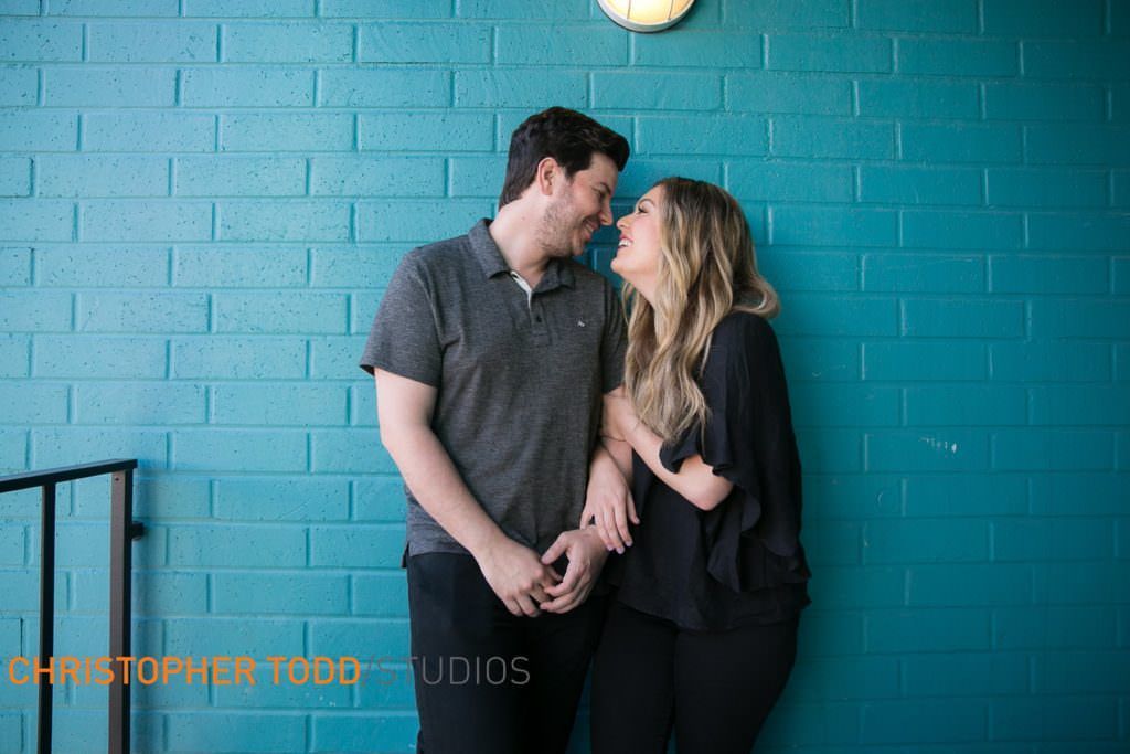 A man and a woman are standing next to each other in front of a blue brick wall at Lido Marina VIllage
