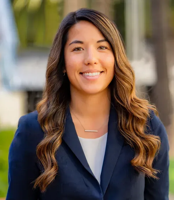 A woman with nice natureal looking makeup in a blue jacket and white shirt is smiling for the camera.