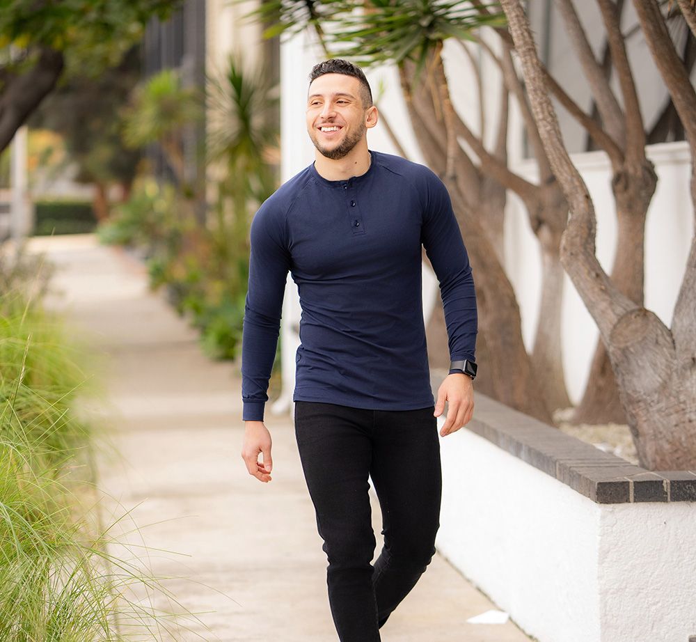 A man in a blue shirt and black pants is walking down a sidewalk