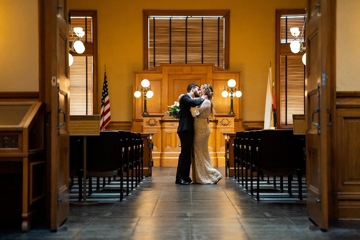 A bride and groom are kissing in a courtroom marriage ceremony 