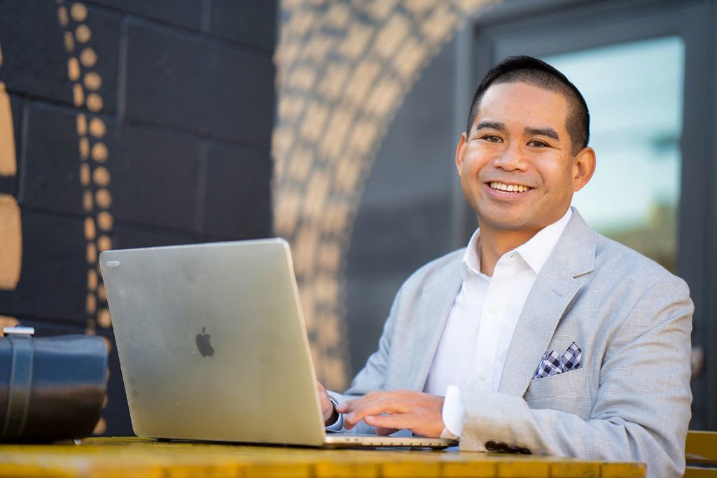 A man in a suit is sitting at a table using a laptop computer.