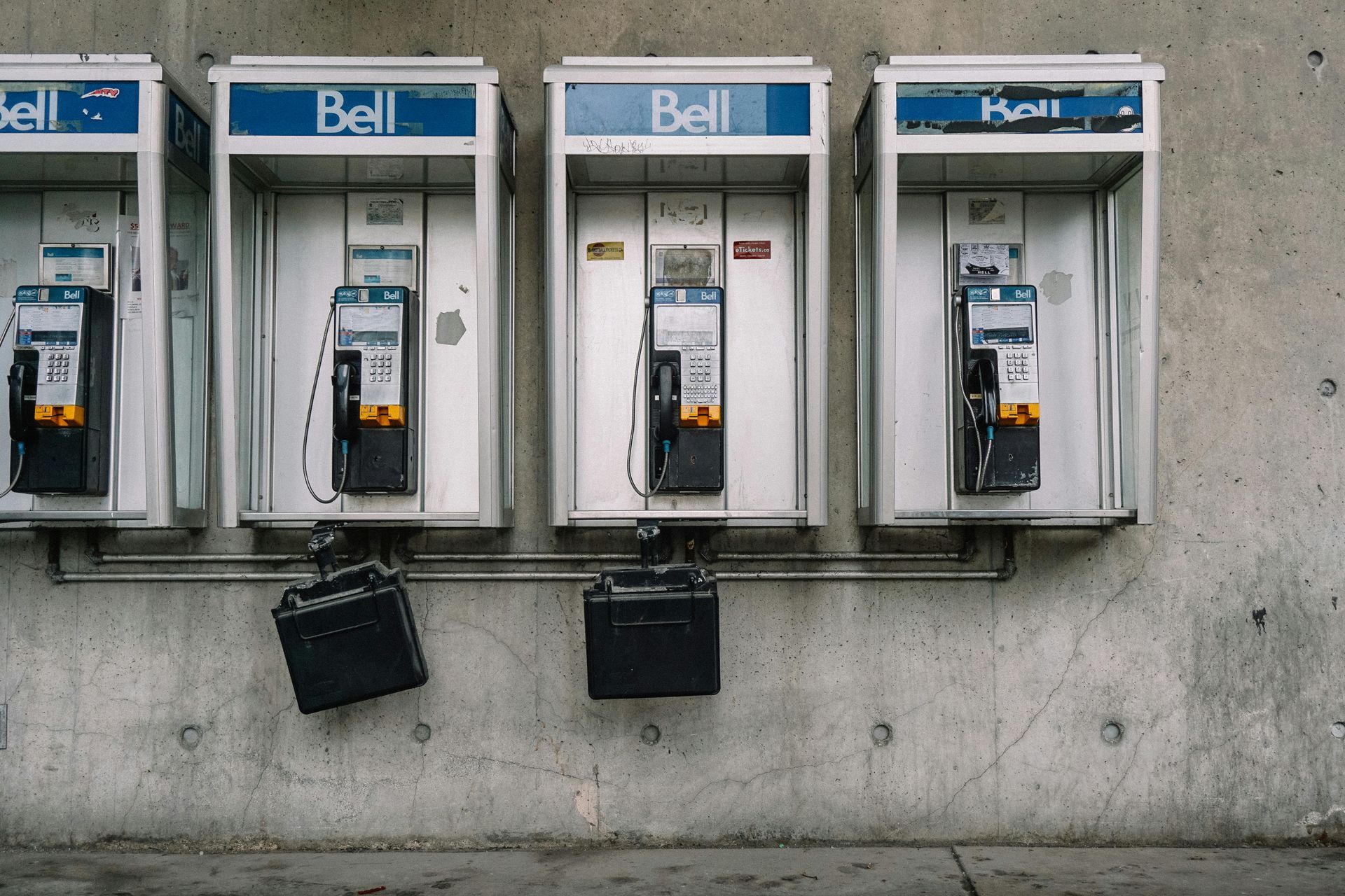 orange county attorney photography Four gray Bell public telephone booths mounted on a concrete wall, with two black boxes hanging beneath them.
