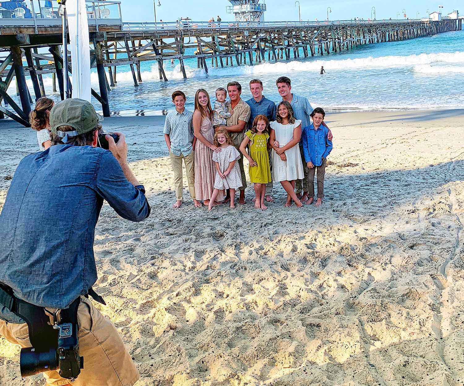 A man is taking a picture of a family on the beach.