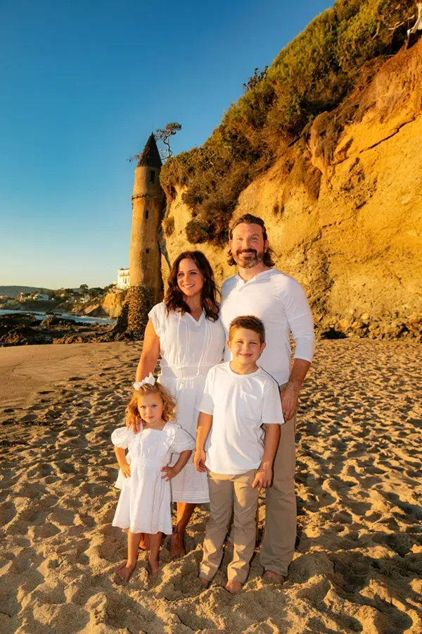 A family is posing for a picture on the beach.