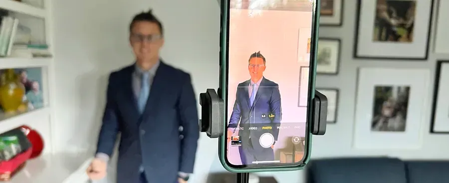 A man in a suit is standing in front of a cell phone.