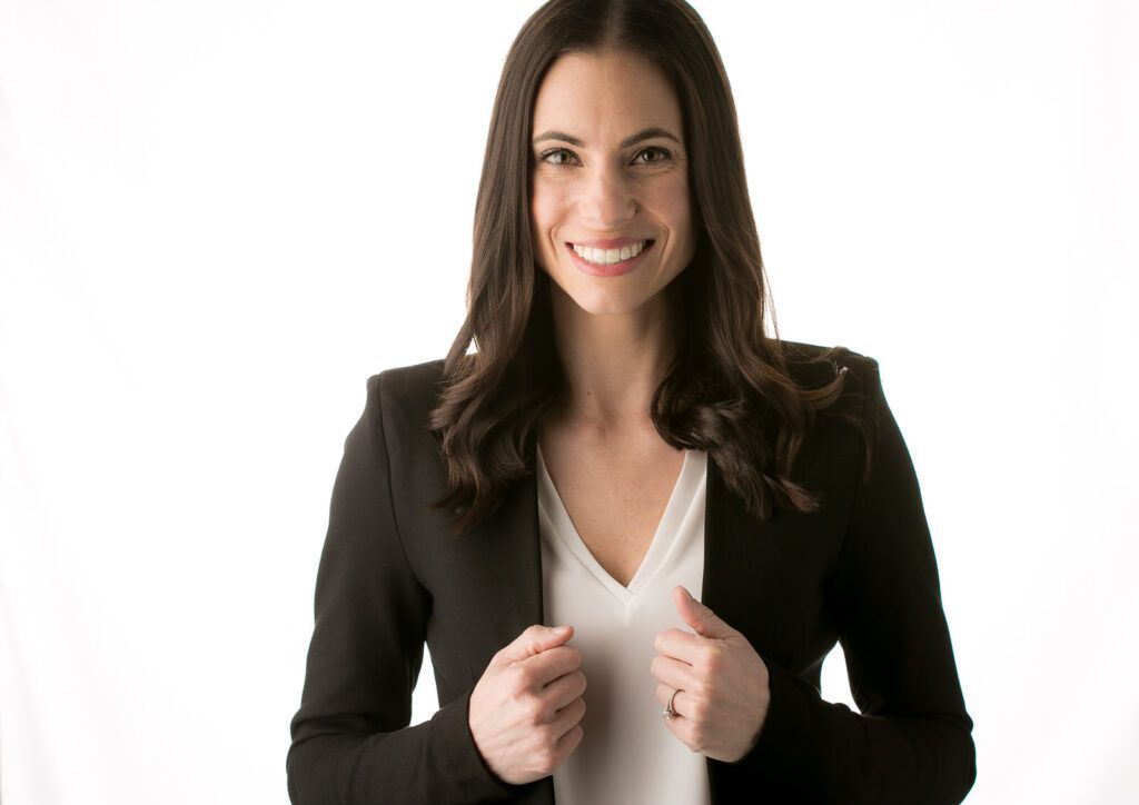 A actress in a black jacket and white shirt is smiling.