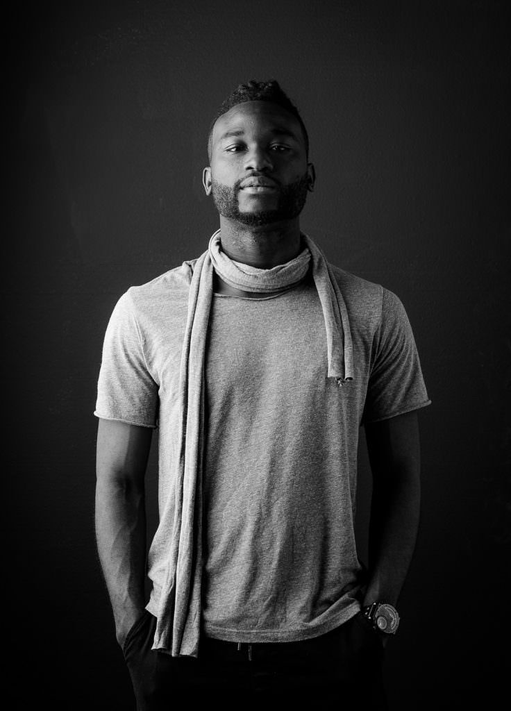 A black and white photo of a man wearing a scarf around his neck.