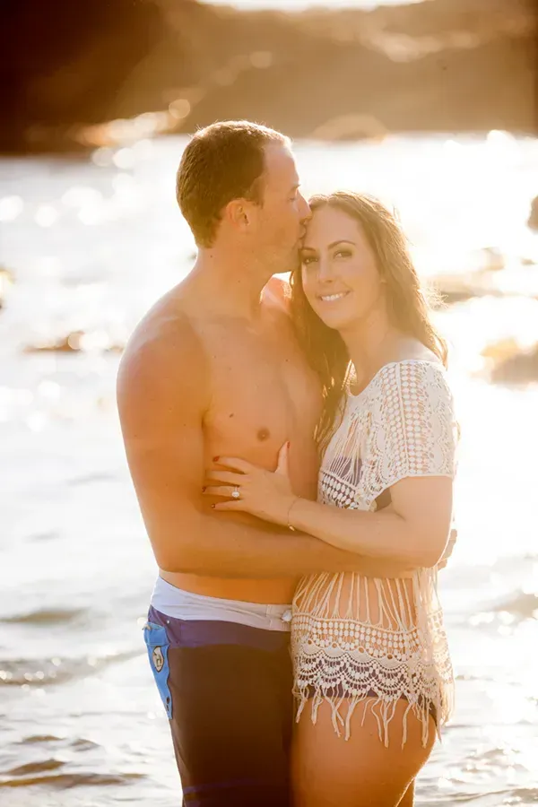 A man and a woman are kissing on the beach.