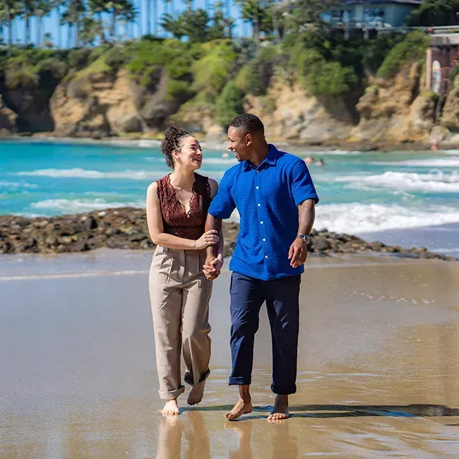 A man and a woman are walking on the Shaws cove in Laguna beach holding hands.