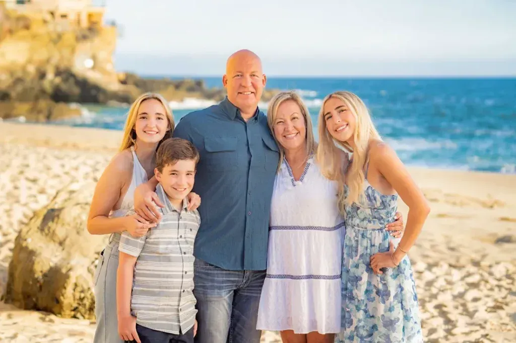 A family is posing for a picture on the beach.