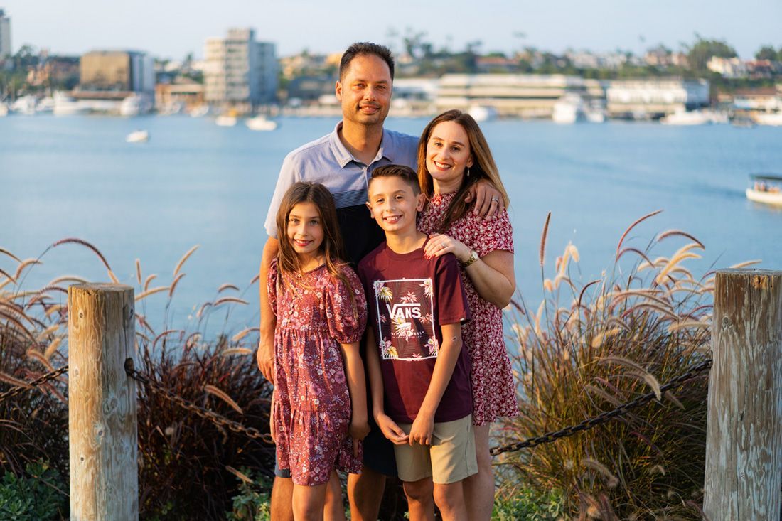 A family is posing for a picture in front of the Newport Beach marina. 