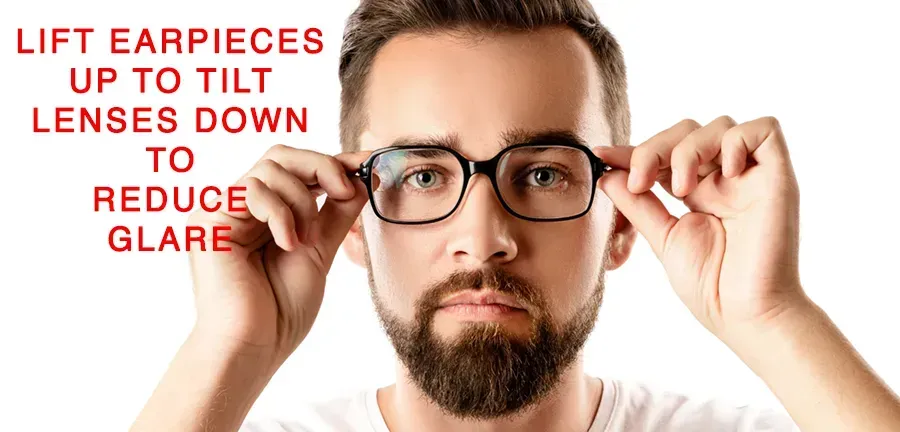 A man with a beard is adjusting his glasses to reduce glare.