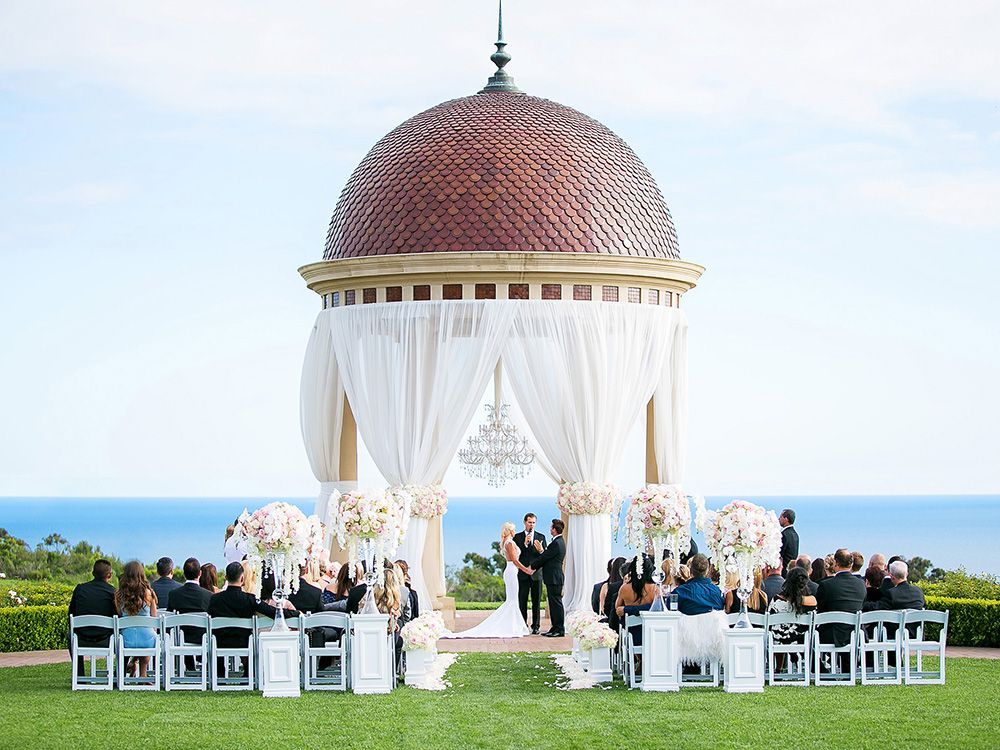 Laguna Beach Wedding Photographer A wedding ceremony is taking place under a gazebo with a view of the ocean.