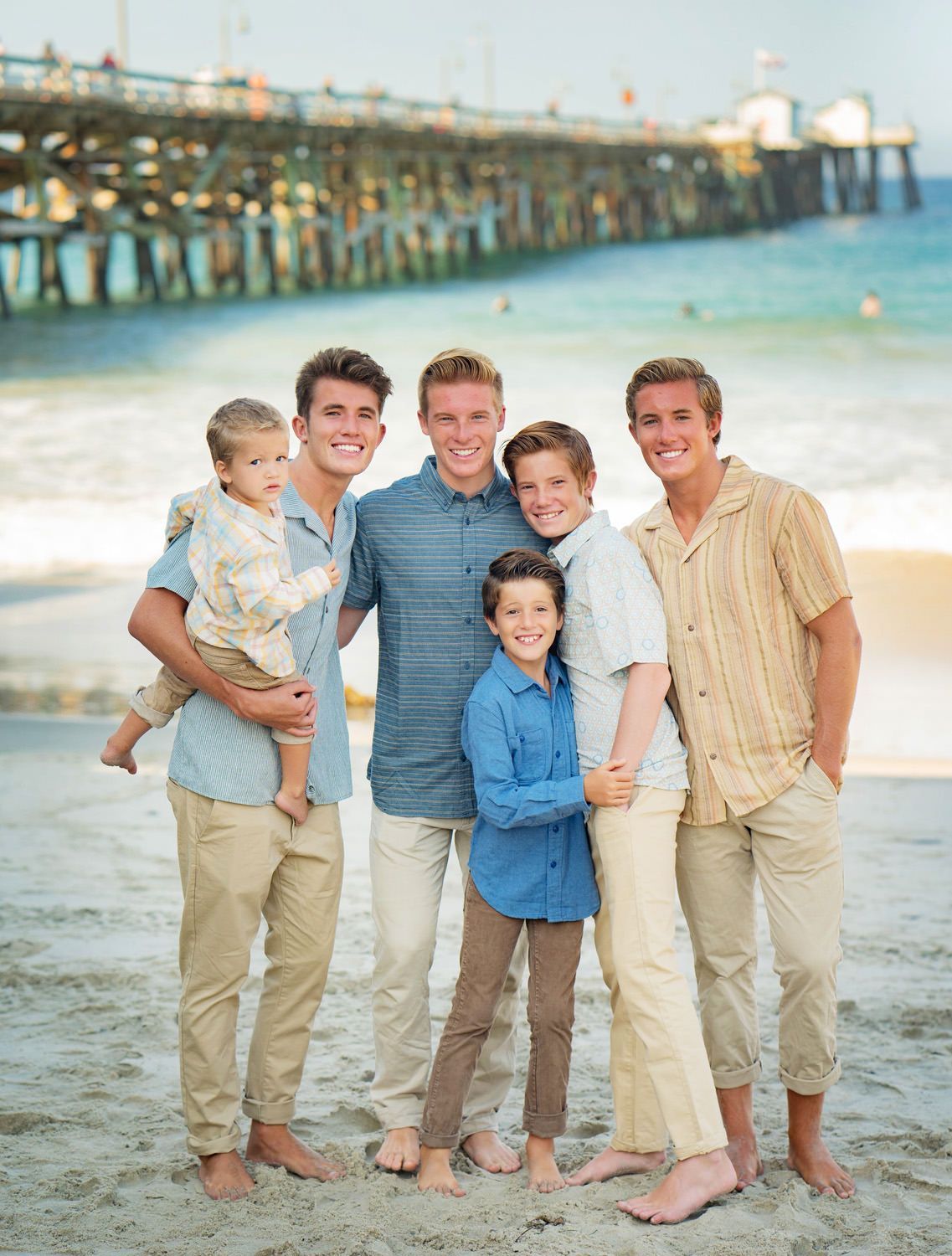 A group of brothers are posing for a picture on the beach.